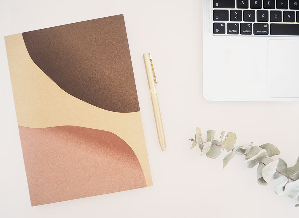 Arbeitsplatz Texterin und Content Creator mit Notizbuch, Stift und Laptop
