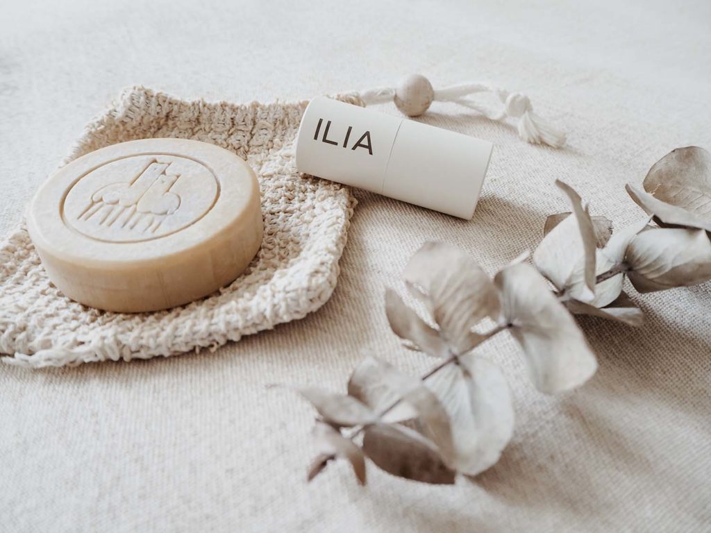 Eco-Friendly Cosmetics Flatlay showing a soap bar and a lipstick next to a green eucalyptus twig.