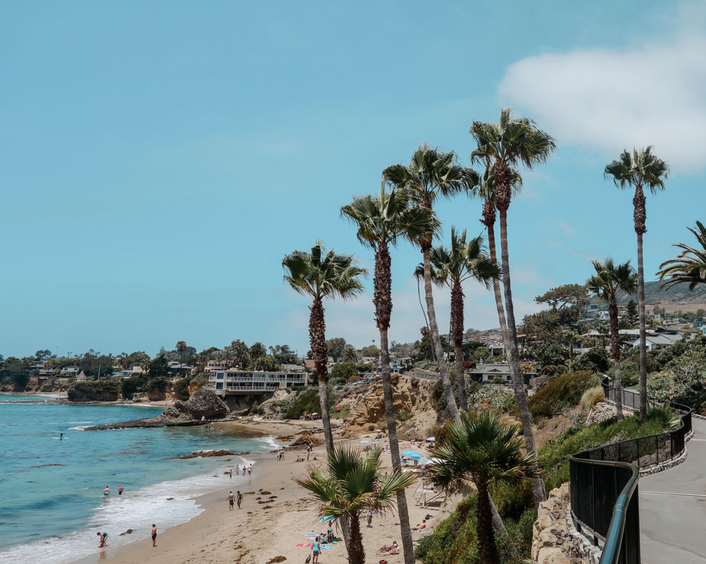 Strand von Laguna Beach mit Palmen, die in den blauen Himmel ragen
